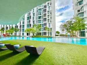 八打灵再也Comfort Place 1-8 Pax 3Q beds Ara Damansara Center的一座大楼前的游泳池,配有躺椅