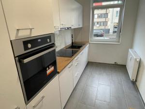 路德维希堡Timeless: Große Moderne 4 Zimmer Wohnung的厨房配有白色橱柜和黑烤箱。