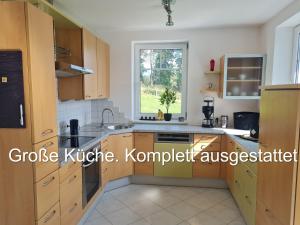 TrattenAparts Lakeview -Gerlitzen -Ossiacher See -Ski的厨房配有木制橱柜和窗户。
