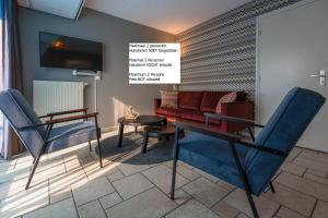 德科赫特塞尔霍夫酒店的一间设有两把椅子、一张桌子和一台电视的房间