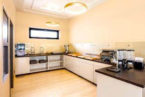 尼赖吉哈佐Ikonik Spa Hotel的厨房配有白色橱柜和黑色台面