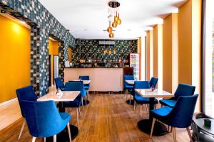 尼赖吉哈佐Ikonik Spa Hotel的一间设有蓝色桌椅的餐厅和一间酒吧