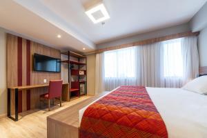阿雷格里港Hotel Laghetto Stilo Higienópolis的配有一张床和一张书桌的酒店客房