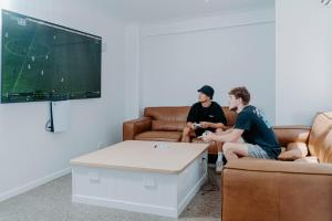 黄金海岸Surf Inn Boutique Backpackers - FREE BREAKFAST的两个男人坐在客厅里玩电子游戏