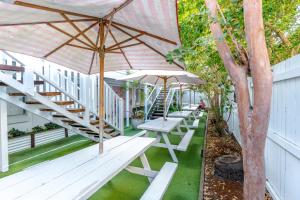 黄金海岸Surf Inn Boutique Backpackers - FREE BREAKFAST的庭院里一排带遮阳伞的野餐桌