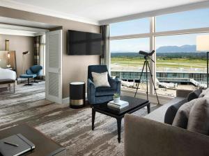 里士满温哥华机场航站楼费尔蒙酒店的一间客厅,客厅配有沙发和电视,位于酒店的房间