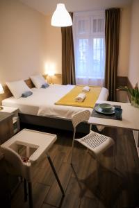 布达佩斯East Station Comfort Plus的酒店客房带一张床、一张桌子和椅子
