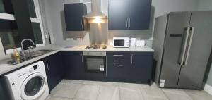 考文垂Coventry Rise Home的厨房配有蓝色橱柜、炉灶和微波炉。