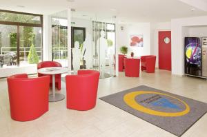 蒙德塞月亮湖青年旅舍的大堂设有红色椅子、桌子和地毯