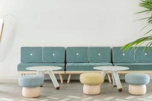 锡切斯特乐玛ME锡切斯酒店的绿色沙发,带两张桌子和两张凳子