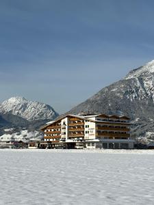 齐勒谷地施特拉斯Hotel Cafe-Zillertal的一座大建筑,位于雪覆盖的山前