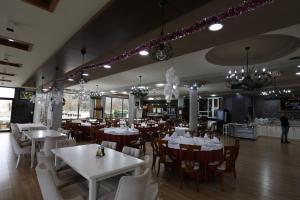 波格拉德茨Hotel 1 Maji的餐厅设有白色的桌椅和吊灯。