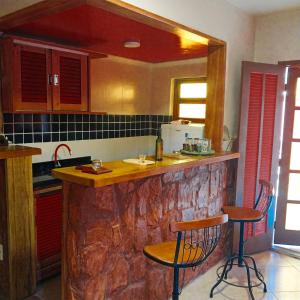 布希奥斯Super Flats Geribá的厨房配有石制柜台和2个酒吧凳