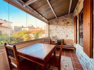 福卡Time Traveler's House - Eski Foça的阳台设有木桌和大窗户。