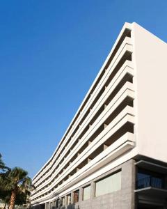 海若克利欧拉奎拉亚特兰蒂斯酒店的蓝天前有棕榈树的白色建筑