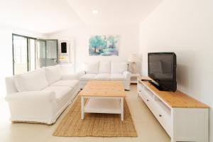 塞维利亚Alojamiento Rural Finca Barral的客厅配有白色家具和平面电视