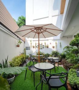 曼谷ZEN MASTER HOTEL的一个带桌椅和遮阳伞的庭院