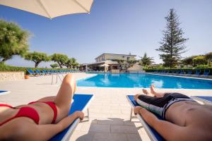 梵蒂冈角Hotel Villaggio Roller Club的两人躺在游泳池边的躺椅上