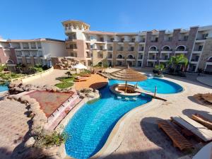 赫尔格达Royal Beach Private Apartments Hurghada的一个带椅子和遮阳伞的游泳池的度假酒店