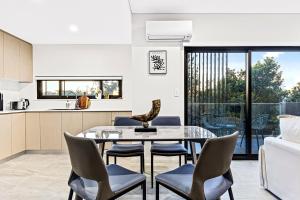 悉尼Urban Oasis in Heart of Homebush的厨房以及带玻璃桌和椅子的用餐室