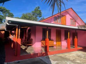 福尔图纳Casa Nativo Spring Arenal的粉红色的房子,前面有长凳