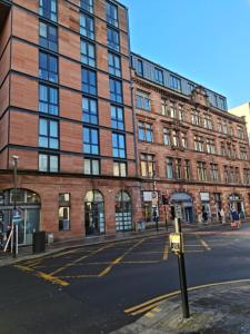 格拉斯哥VCity ApartHotels Glasgow Central的街道上高大的砖砌建筑,有停车计