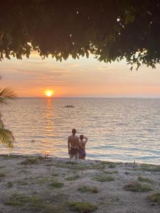 埃尔莱马特Bikini Beach的两个人站在海滩上欣赏日落