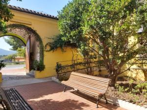 FanzaraEl Castellet Fanzara的坐在黄色建筑旁的长凳,有树