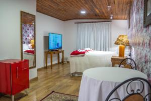 坎波斯杜若尔当阿斯科纳酒店的一间卧室配有一张床、一台电视和一张桌子
