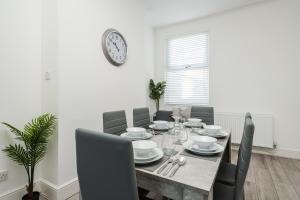 利物浦Hornsey Lodge - Anfield Apartments的餐桌、椅子和墙上的时钟