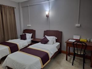艾藻尔Hotel Chhungte International的酒店客房配有两张床和一张书桌
