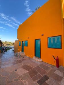 阿斯旺Fenti Nubian Resort的橙色的建筑,设有蓝色的门窗