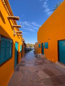阿斯旺Fenti Nubian Resort的两栋建筑之间的一条小巷,两栋建筑的墙壁很橙色
