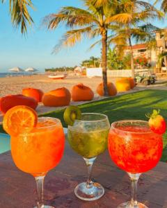 伊卡莱Pousada Casa Canto das Águas的海滩附近的餐桌上喝着三杯酒杯鸡尾酒