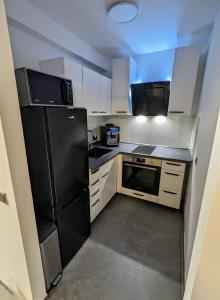 科尔恩韦斯泰姆View的厨房配有黑冰箱和白色橱柜。