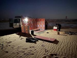 Qasr Al FarafirahWhite desert & Black desert camb的站在海滩帐篷前的人