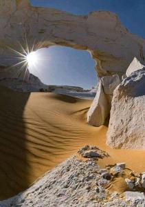 Qasr Al FarafirahWhite desert & Black desert camb的阳光照耀着沙中的拱门的沙漠