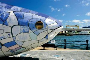 贝尔法斯特Central Haven的坐在长凳旁的彩色玻璃鱼雕塑