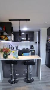 TocancipáTOCANCIPÁ, Increíble, Hermoso y Moderno APARTAMENTO COMPLETO!的厨房配有柜台和2个酒吧凳