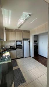 蓬塔格罗萨Ap Central c/ Garagem的厨房配有木制橱柜和白色冰箱。