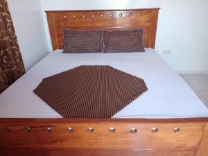 Sere KundaSuleimane guest的一张带木制床头板和白色床单的床