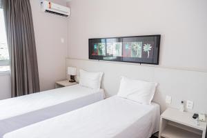 孔塔任Hotel Eldorado Flat的两张床铺,位于酒店客房,墙上配有电视