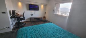 圣地亚哥Hermoso y acogedor Apartamento的一间卧室配有一张床、一台电视和一张书桌