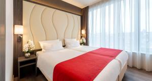 海牙Best Western Plus Plaza Den Haag City Center的一间卧室配有一张带红色毯子的大床