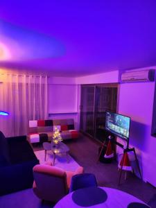 巴黎Appart'Chic的客厅配有紫色照明和电视