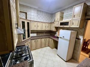 开罗NEAR THE PYRAMIDS Inn的厨房配有木制橱柜和白色冰箱。