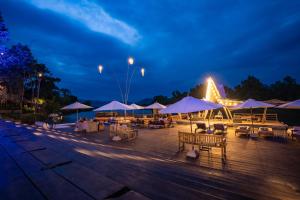 贡布Devi Kampot Resort at Phum Kampot的夜间带桌椅和遮阳伞的甲板