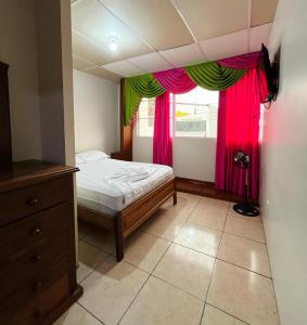 佩德纳莱斯CASA DE HOSPEDAJE PEDERNALES的一间卧室设有床铺和窗户,窗户配有粉红色和绿色的窗帘