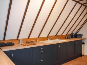 AshburnhamKingfisher Granary的厨房配有黑色橱柜和水槽