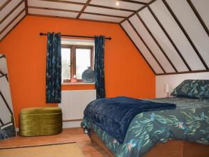 AshburnhamKingfisher Granary的一间卧室拥有橙色的墙壁、一张床和窗户